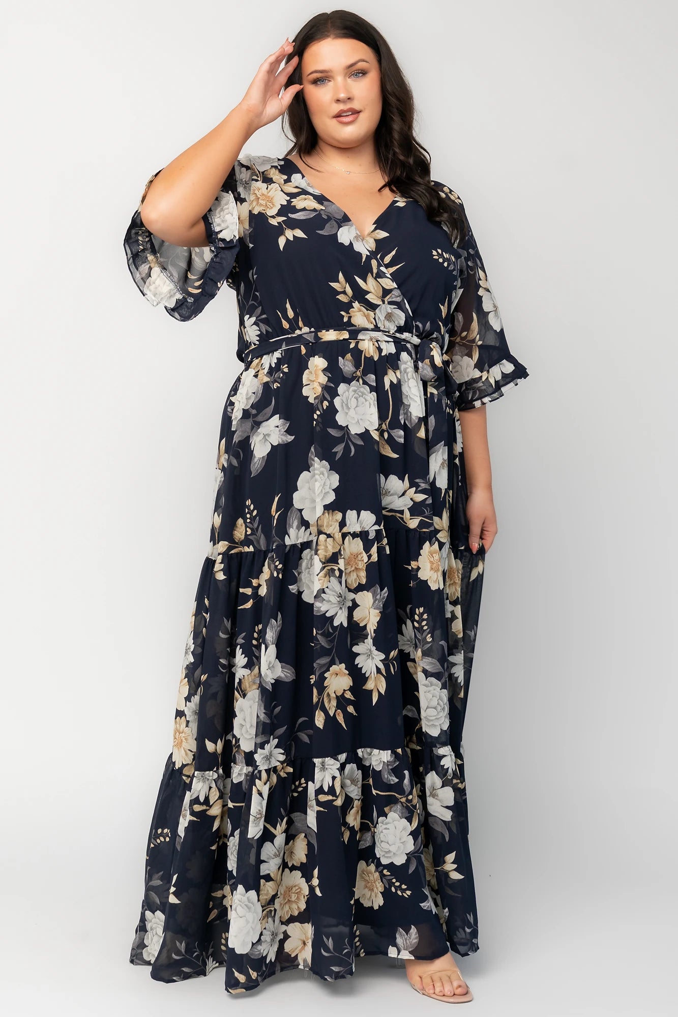 Model wearing the Luna Maxi Dress in Navy Floral featuring a surplice V-neckline with a V-back and tie detail, soft flutter sleeves, and an elastic waist with a removable sash tie