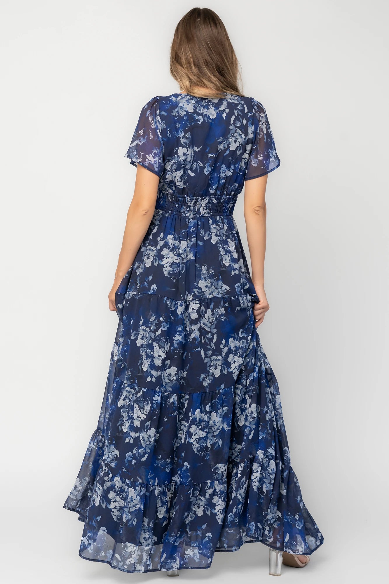 Blue floral chiffon maxi dress with flutter sleeves, surplice V-neck, smocked elastic waist, tiered skirt, and lined body.