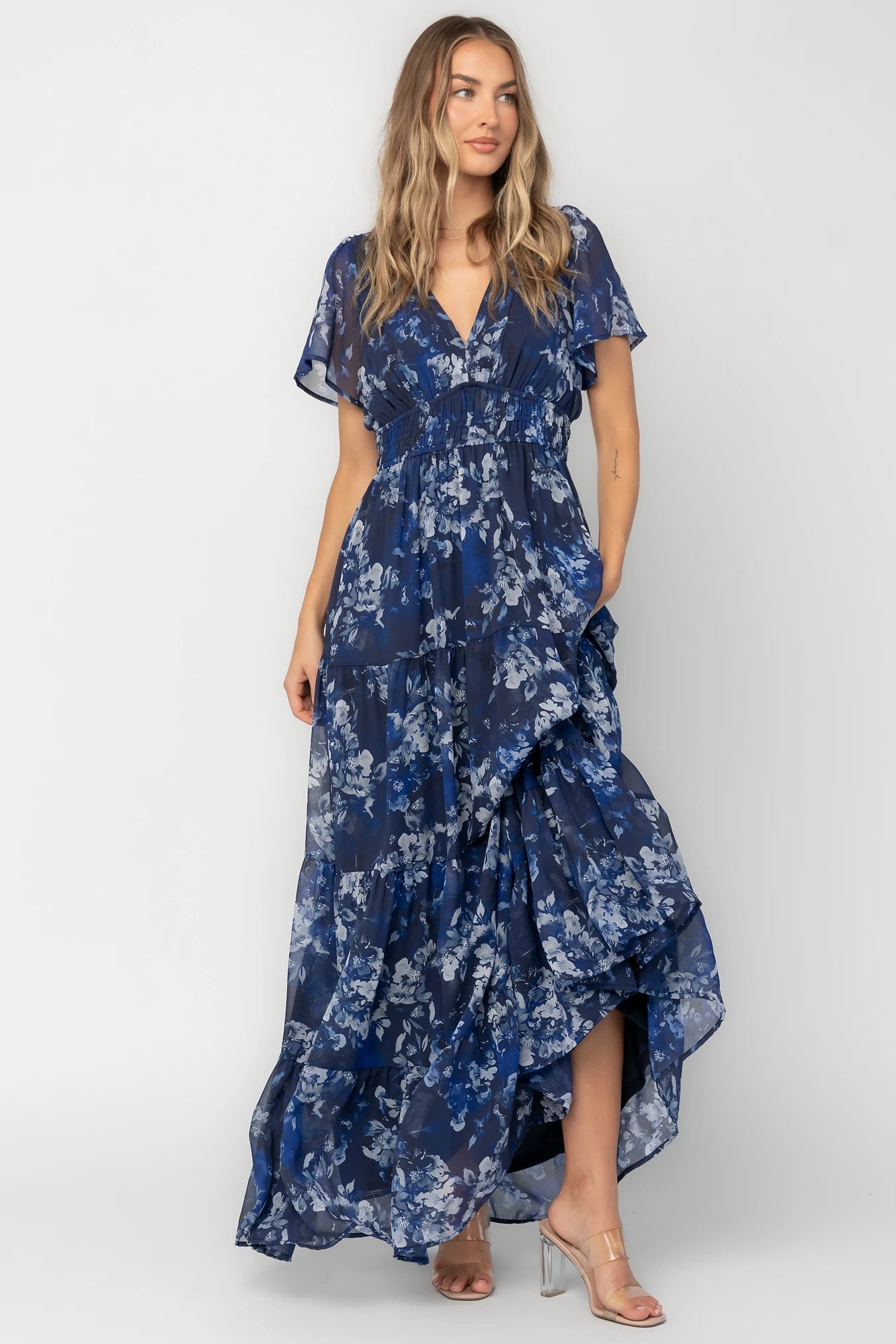 Blue floral chiffon maxi dress with flutter sleeves, surplice V-neck, smocked elastic waist, tiered skirt, and lined body.