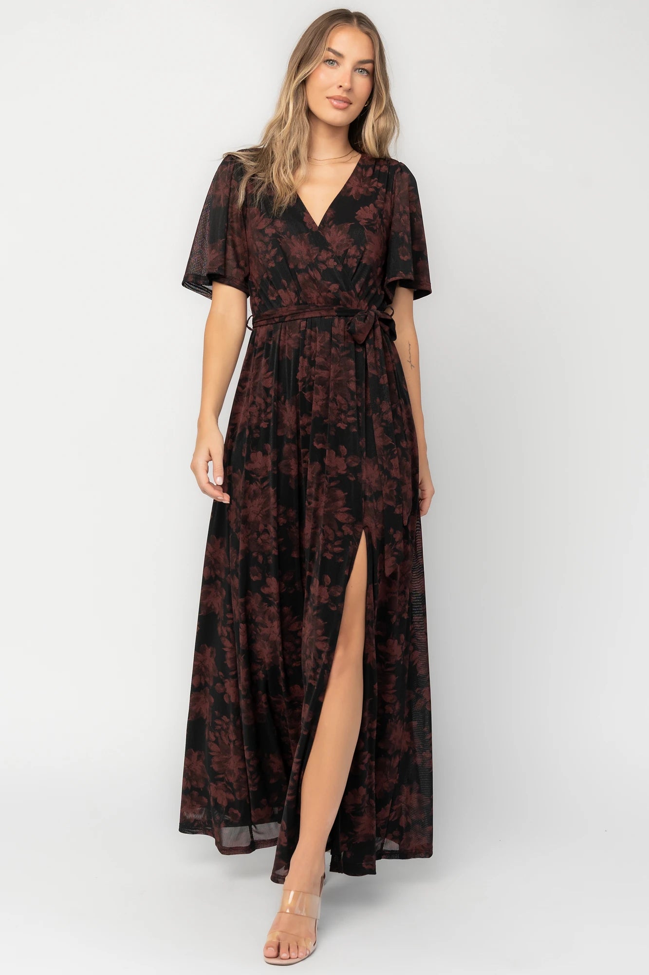 Black and burgundy floral shimmer maxi dress with flutter sleeves, surplice V-neck, elastic waist, removable sash, and side leg slit.