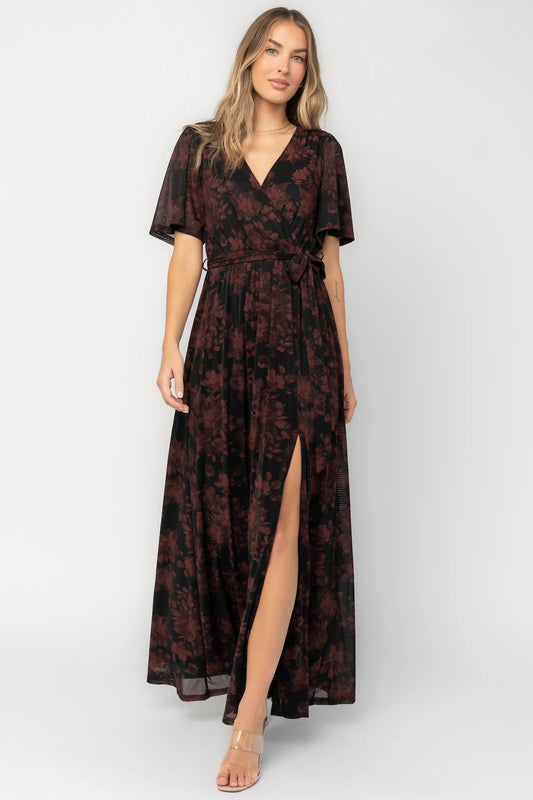 Black and burgundy floral shimmer maxi dress with flutter sleeves, surplice V-neck, elastic waist, removable sash, and side leg slit.