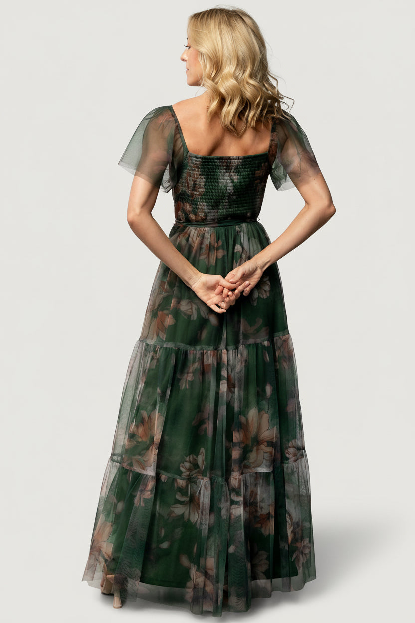Full-length image of Nicola Tulle Maxi Dress in deep green floral on model, illustrating tiered skirt and raw hem movement.