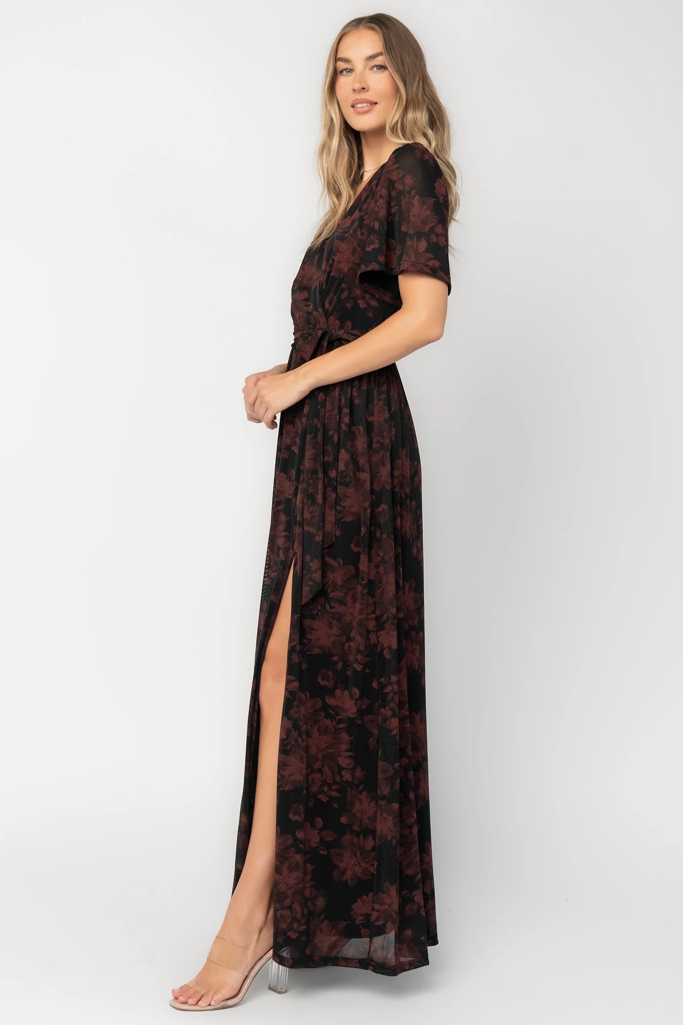Black and burgundy floral shimmer maxi dress with flutter sleeves, surplice V-neck, elastic waist, removable sash, and side leg slit.