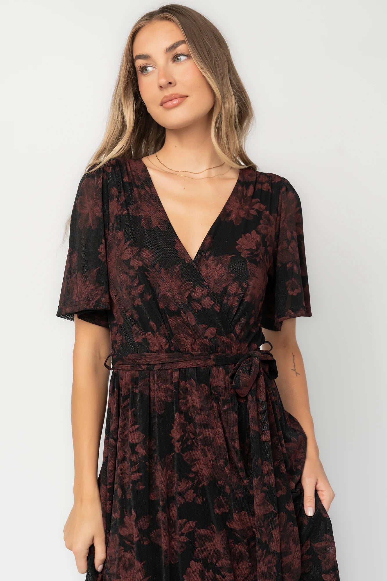 Black and burgundy floral shimmer maxi dress with flutter sleeves, surplice V-neck, elastic waist, removable sash, and side leg slit.