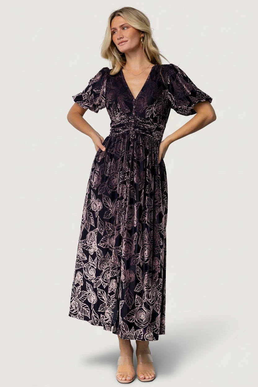 Front view of Dahlia embossed velvet maxi dress in indigo and purple floral, showing V-neck, faux-button placket, short puff sleeves, and pockets.