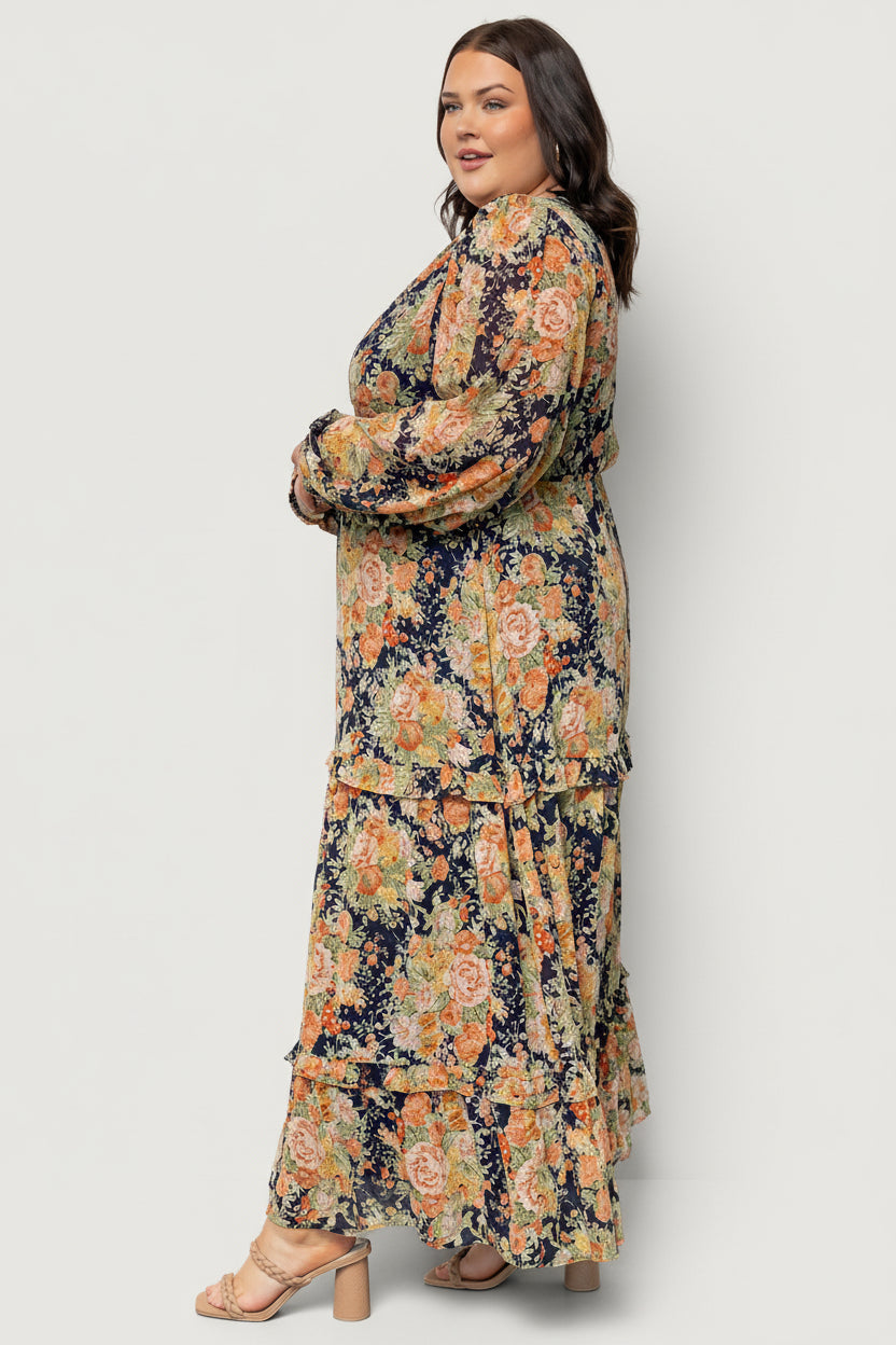 Lifestyle image of navy floral maxi dress worn with sandals, showing drape, movement and occasion-ready styling.