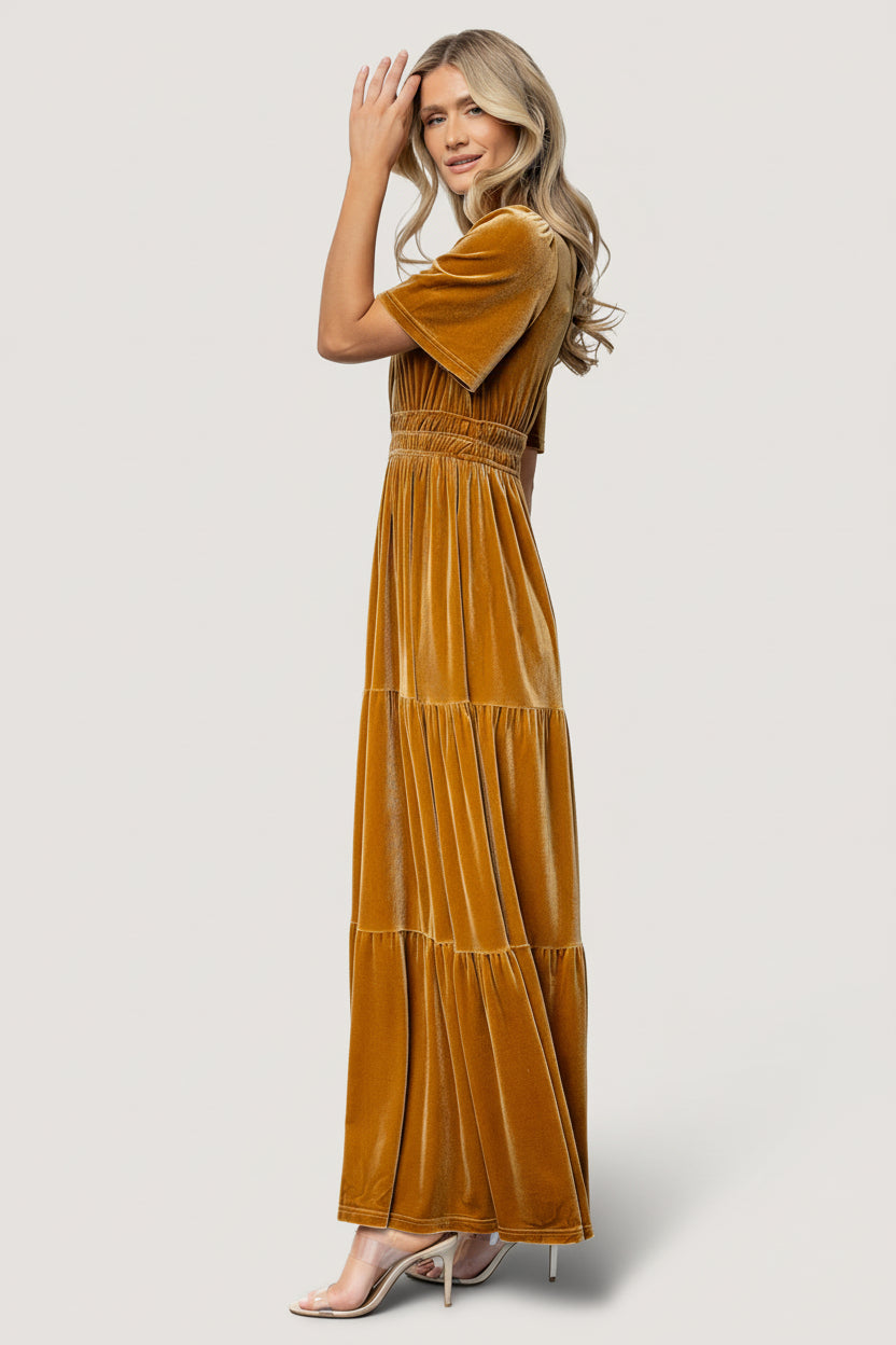 Close-up detail of the elastic gathering at the waist and rich dark-gold velvet fabric, showing texture and stitching quality under natural light.