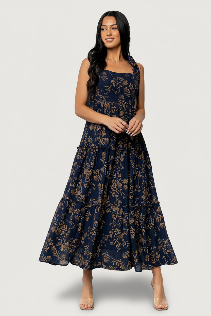 Front view of Anita Maxi Dress in midnight blue with gold floral print, showing square neckline, paneled bodice, and three-tier ruffled maxi skirt.