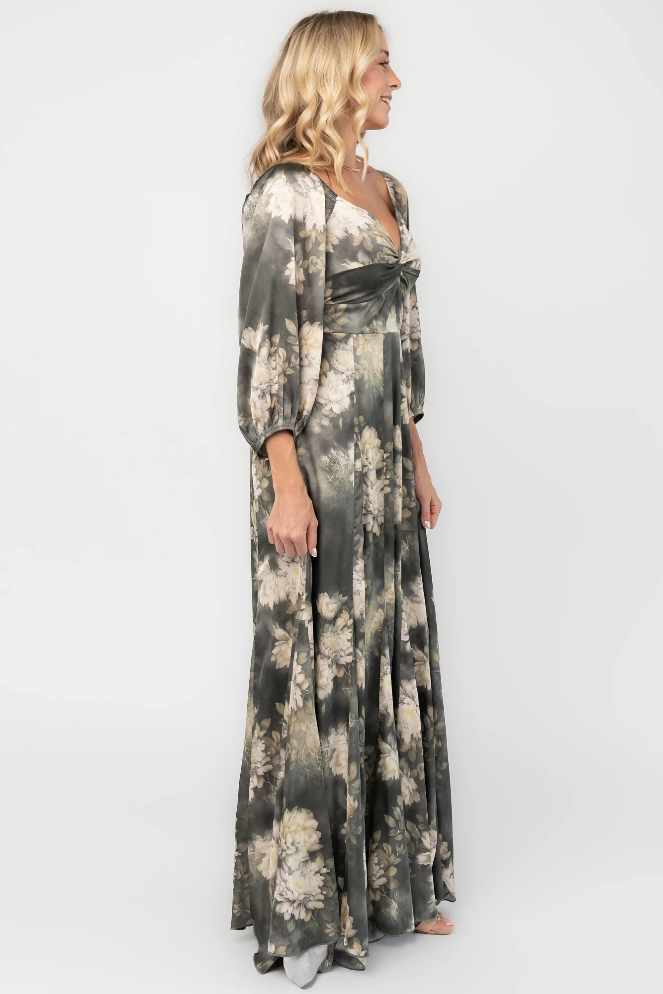Dark sage floral maxi dress with a V-neck twist knot, half sleeves, smocked back waist, paneled empire waist, and flowing scalloped asymmetrical hem.
