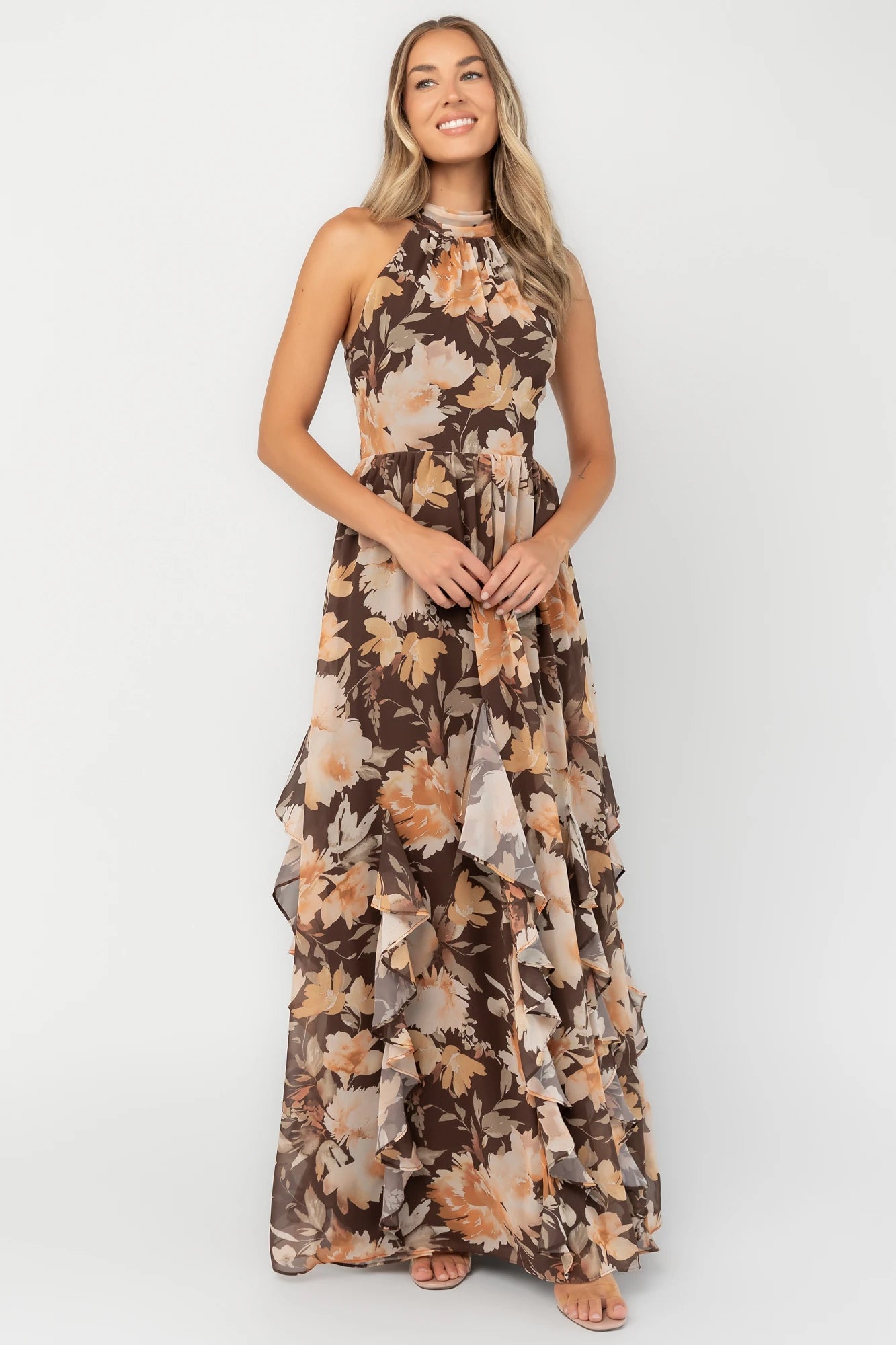 Brown and golden floral chiffon maxi dress with a high halter neckline, cascading ruffle details, smocked back waistband, and a flowing silhouette.