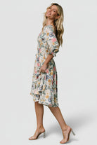 Side profile of the tiered midi dress highlighting the flowing silhouette, waistline fall, and layered skirt movement.