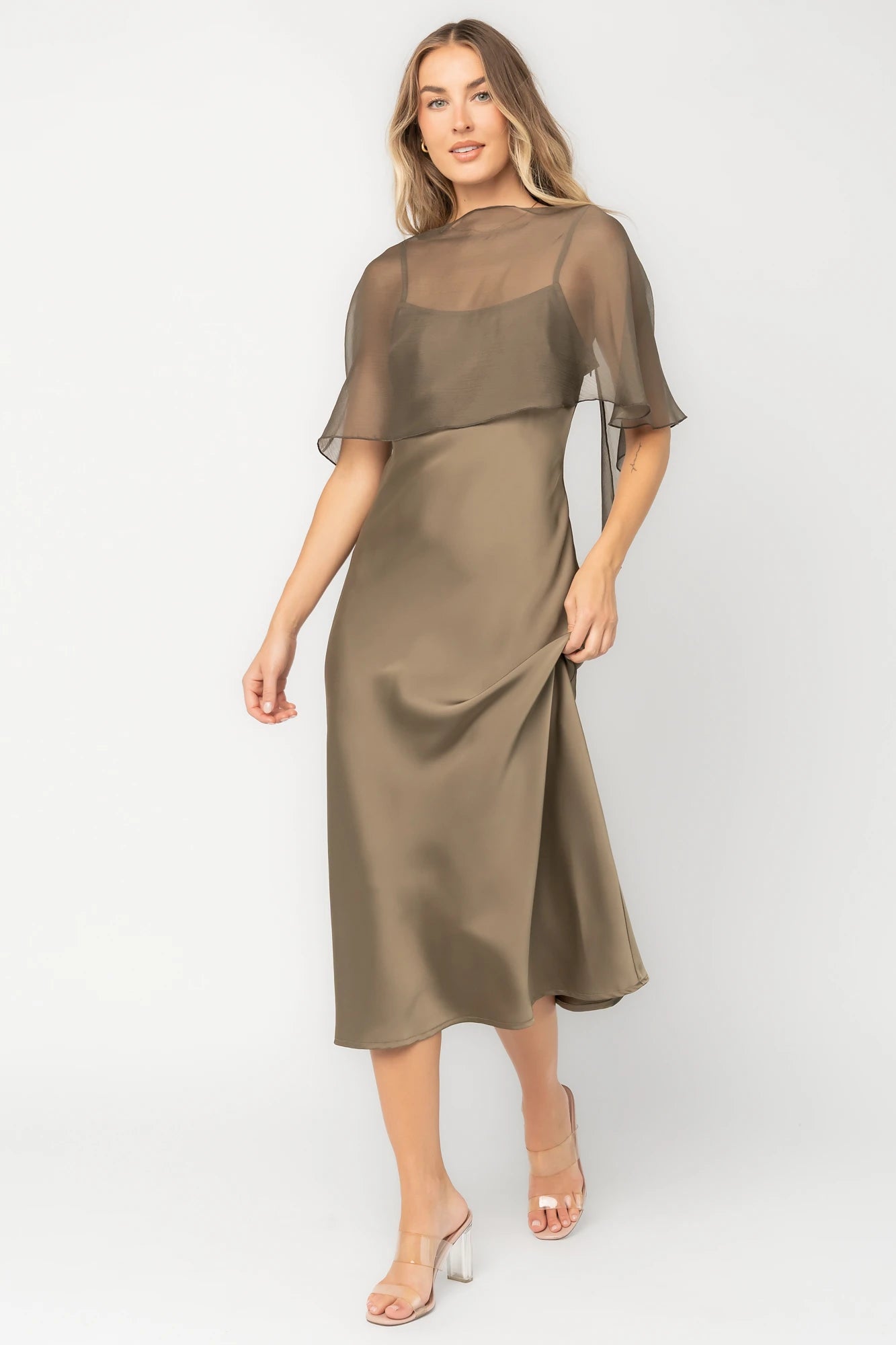 Olive satin midi dress with an attached sheer chiffon cape overlay, round neckline, hidden side zipper, and elegant slip silhouette.