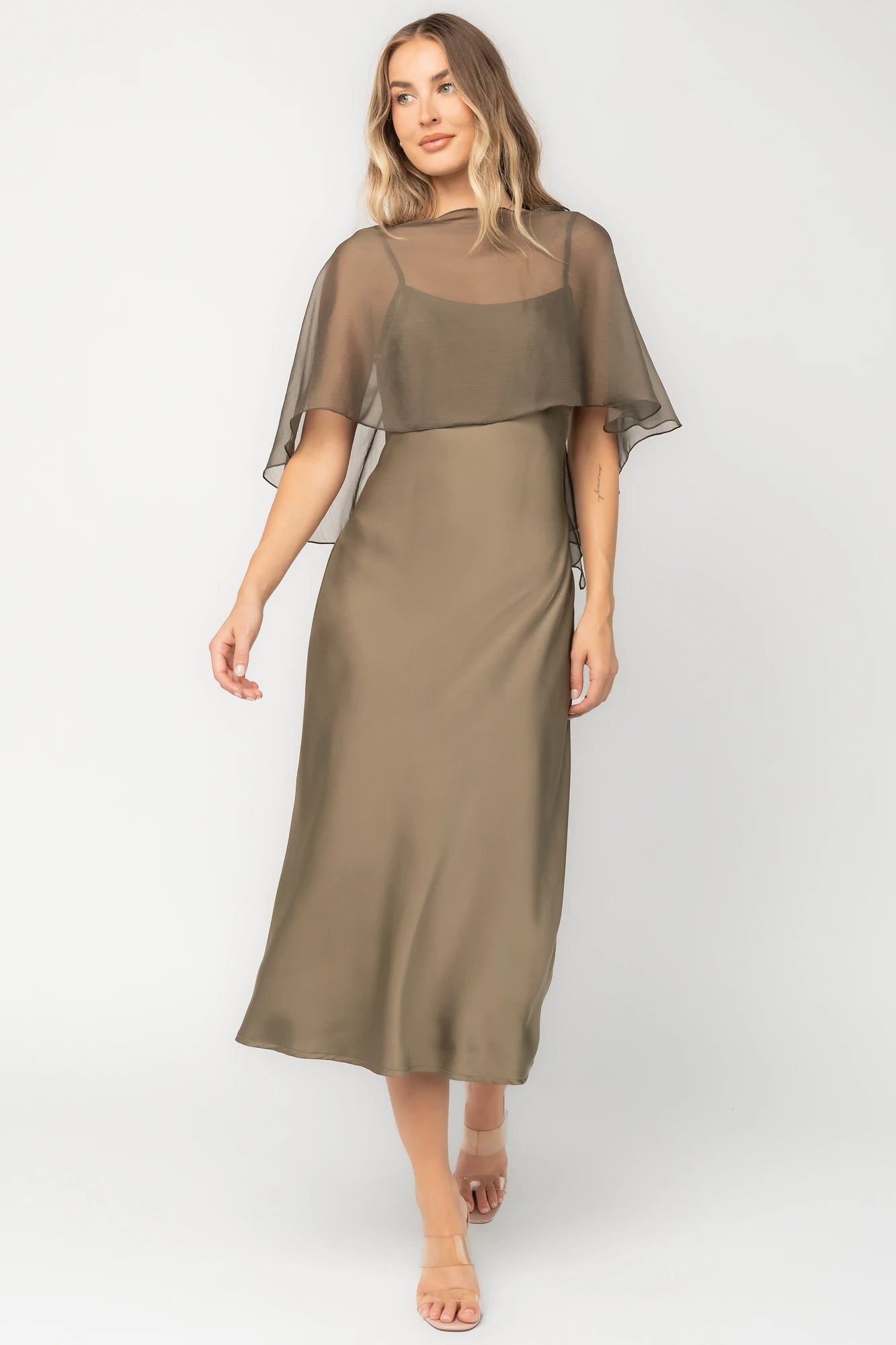 Olive satin midi dress with an attached sheer chiffon cape overlay, round neckline, hidden side zipper, and elegant slip silhouette.