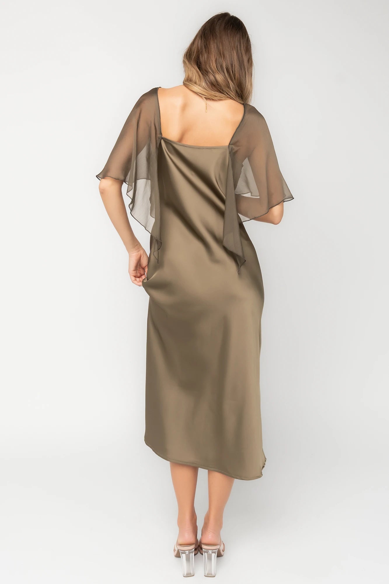 Olive satin midi dress with an attached sheer chiffon cape overlay, round neckline, hidden side zipper, and elegant slip silhouette.
