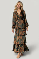 Full-length shot of Montrouge olive floral dress on model with V-neckline, flowing tiers, and elegant movement suitable for weddings and events.