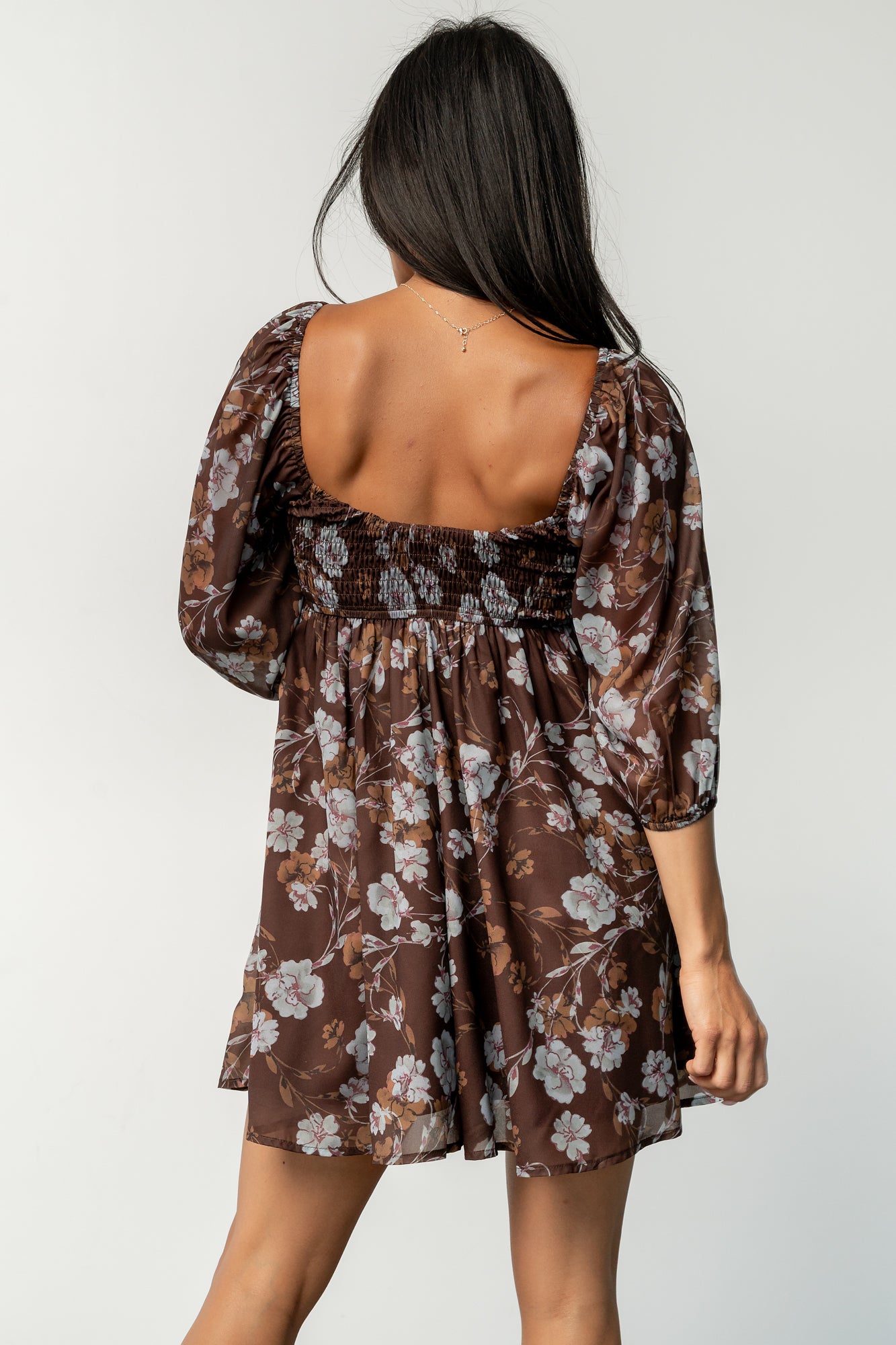 Model seated wearing the Amalia romper, highlighting the wide flowy shorts that mimic a mini dress and relaxed empire waist.