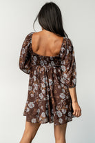 Model seated wearing the Amalia romper, highlighting the wide flowy shorts that mimic a mini dress and relaxed empire waist.