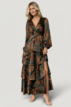 Front view of model in Montrouge olive floral satin tiered maxi dress showing V-neck, short flowy sleeves, and full ruffled skirt; elegant drape and print detail.