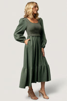 Back view of dusty-green Alva sweater dress revealing skirt tiering, subtle color contrast between bodice and skirt, and comfortable fit.