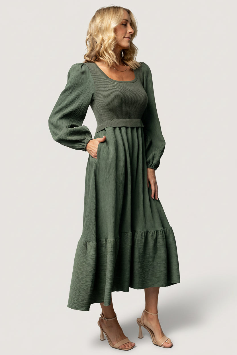 Back view of dusty-green Alva sweater dress revealing skirt tiering, subtle color contrast between bodice and skirt, and comfortable fit.