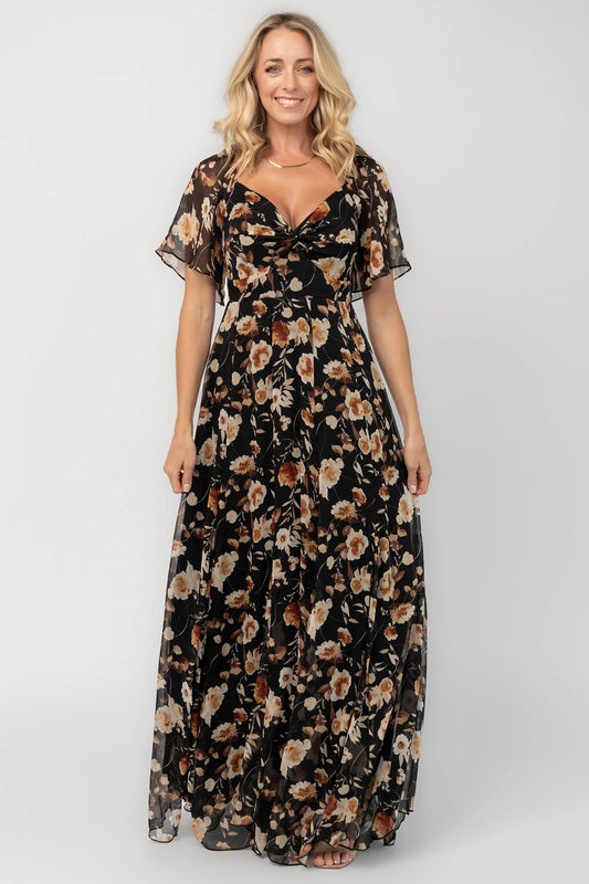 Black floral chiffon maxi dress with a sweetheart neckline, flutter sleeves, smocked back bodice, tiered skirt, and subtle gold foil detailing.