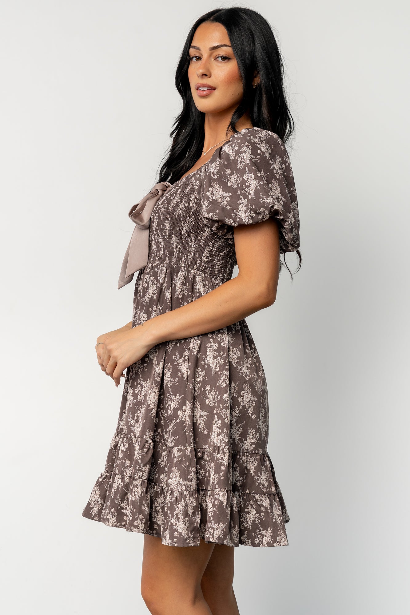 Back and three-quarter view of the Anastasia Bow Short Dress on model, showing overall fit, tiered hem, and full lining for coverage.