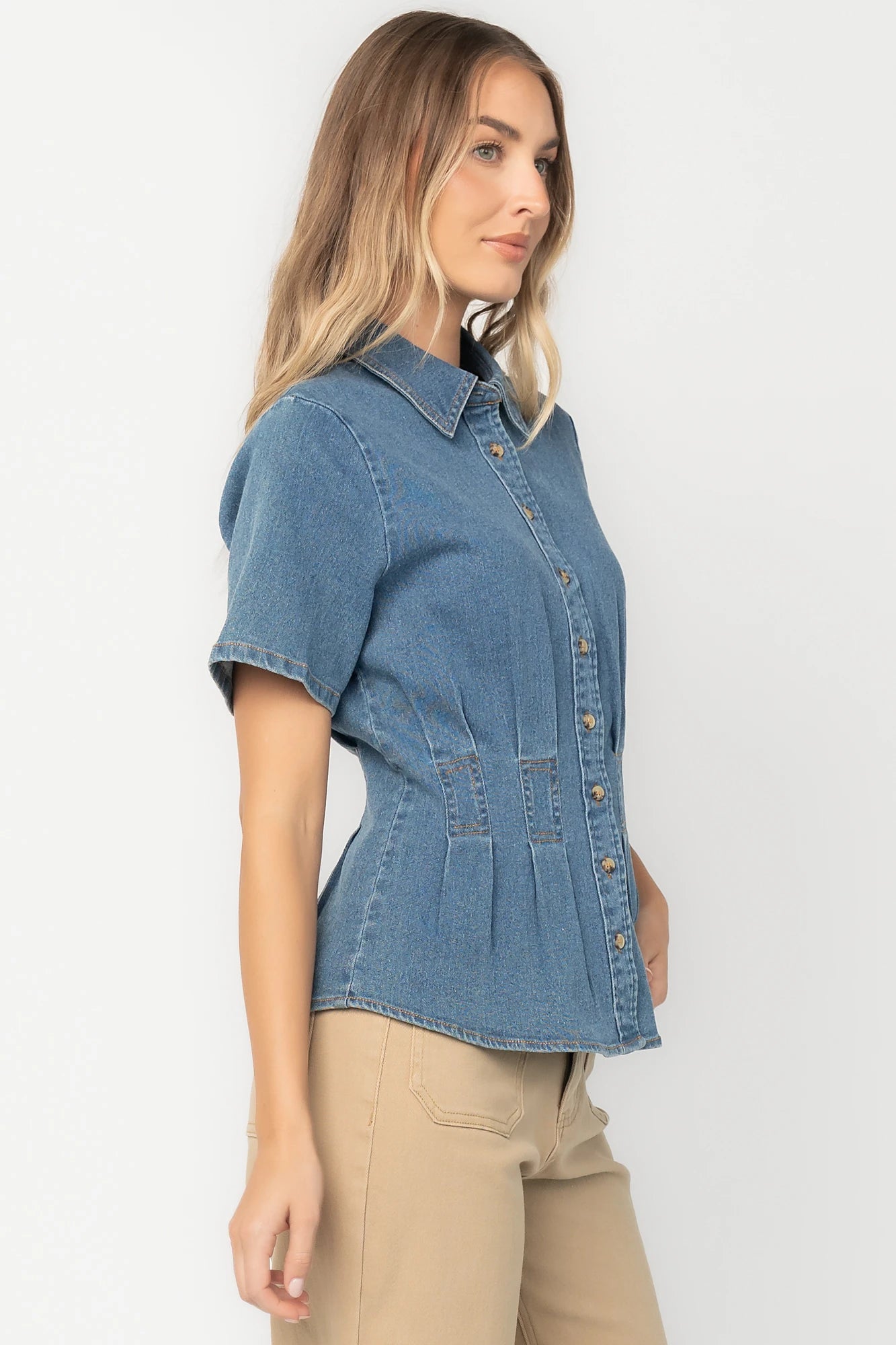 Medium wash stretch denim peplum top with a collared neckline, button-front closure, short sleeves, tailored seam detailing, and a flattering fitted silhouette.
