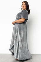 Model movement shot of dusty blue wrap dress illustrating tulip skirt silhouette, tasteful front leg reveal, and how the fabric flows when walking.