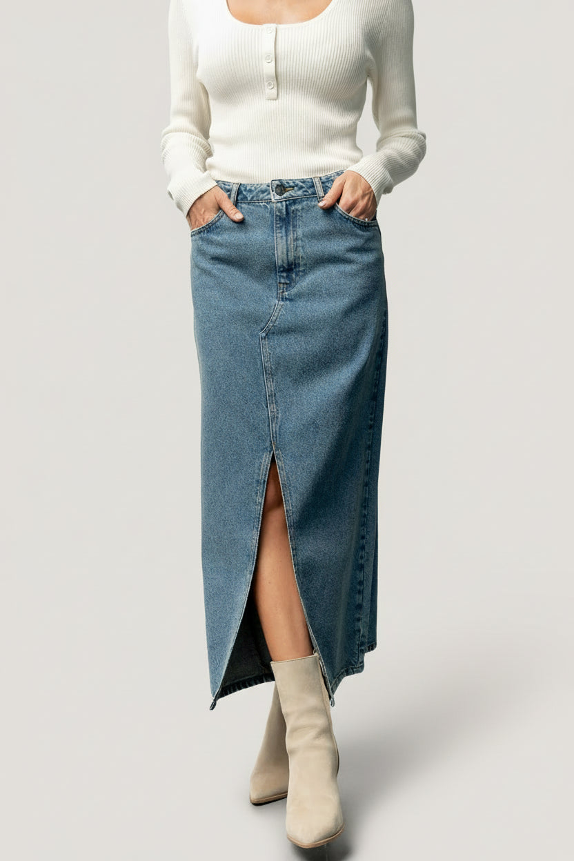Front view of medium wash Aleksa denim midi skirt on model, showing center-front slit, high-rise waist, and functional pockets.
