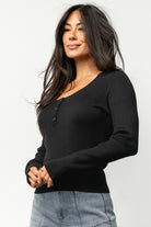 Back view of Leo Ribbed Henley Top in black on model, showing shoulder fit, back hem length, and ribbed knit drape.