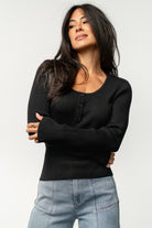 Model wearing Leo Ribbed Henley Top in black tucked into high-rise jeans, styled for a polished casual outfit with subtle texture.