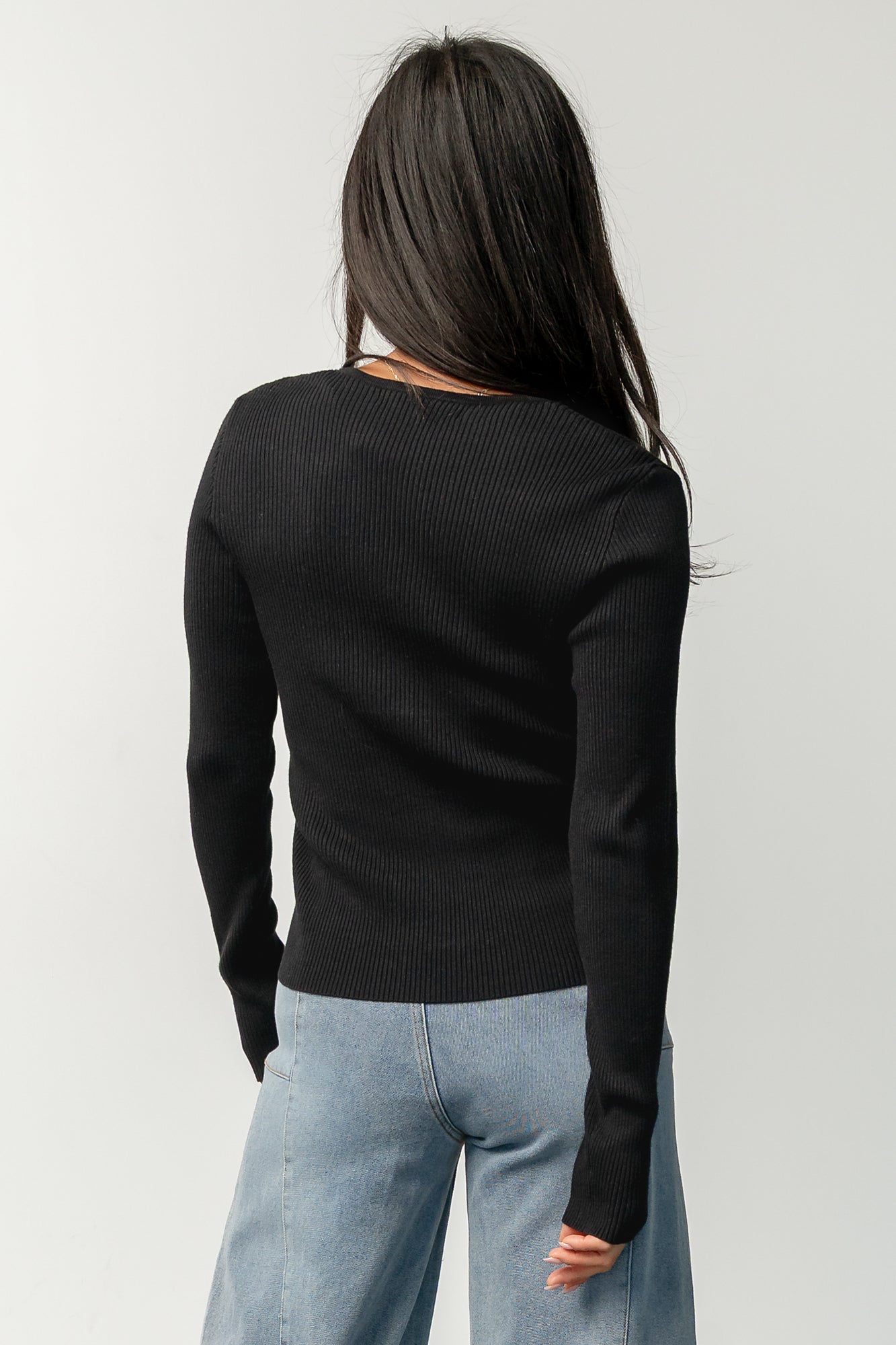 Styled flat-lay of the Leo Ribbed Henley Top in black paired with mid-rise wide leg jeans, showing neckline and hem proportions.