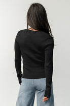 Styled flat-lay of the Leo Ribbed Henley Top in black paired with mid-rise wide leg jeans, showing neckline and hem proportions.