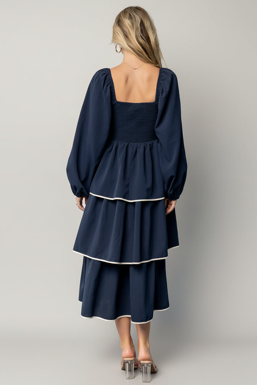 Model walking in navy Barcelona tiered midi dress showing movement of overlapping tiers and soft balloon sleeve silhouette.