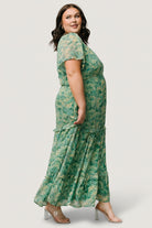 Model walking in green floral chiffon maxi dress, showcasing flow, tiered ruffle structure and the right-side slit in motion.