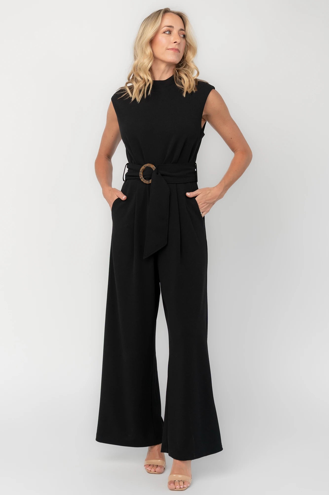 Black tailored wide-leg jumpsuit with a mock neckline, cap sleeves, removable tortoise buckle belt, and side pockets.