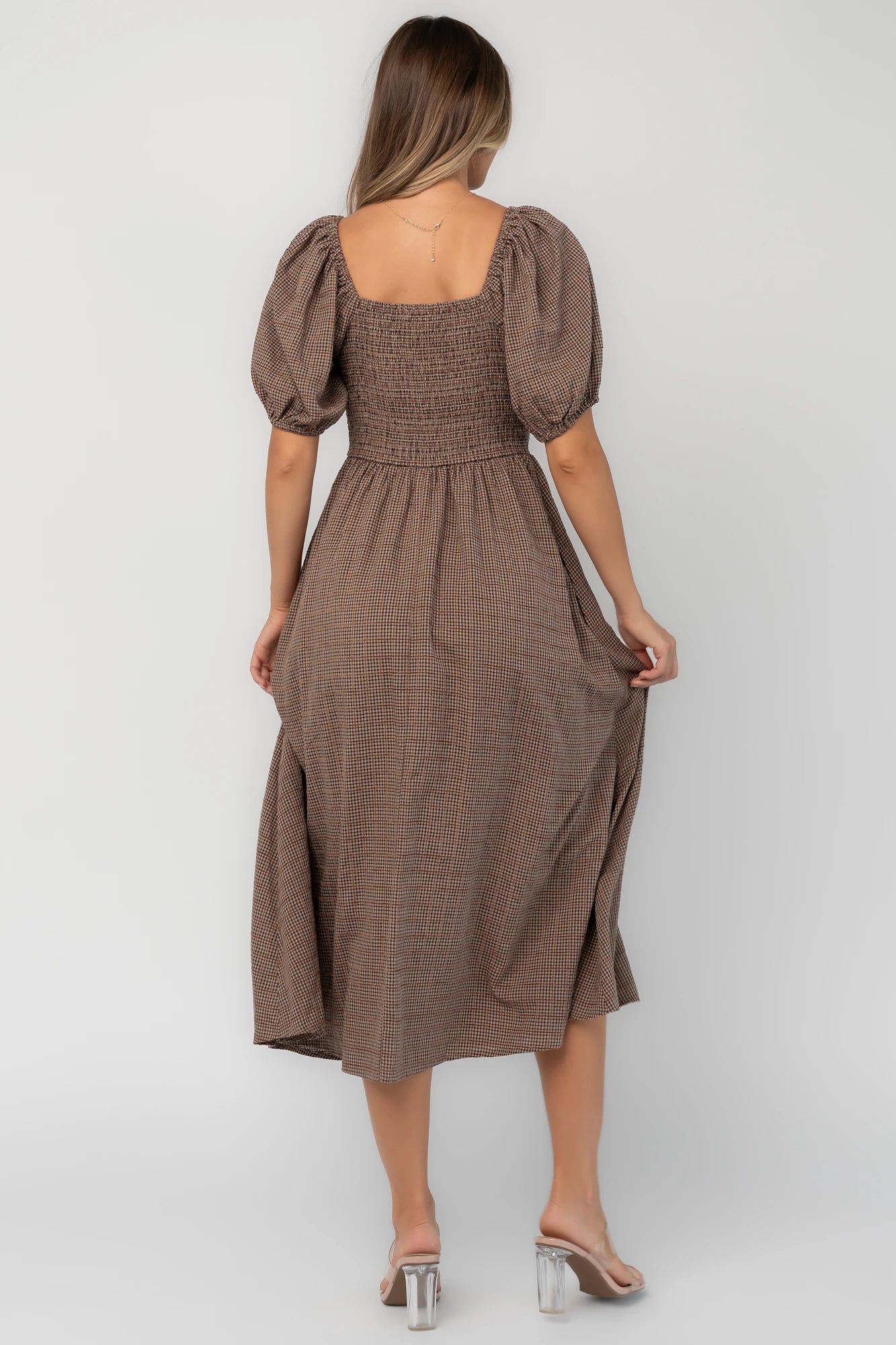 Mocha gingham midi dress with a square neckline, puff sleeves, smocked back, side pockets, and a flowing tiered skirt.