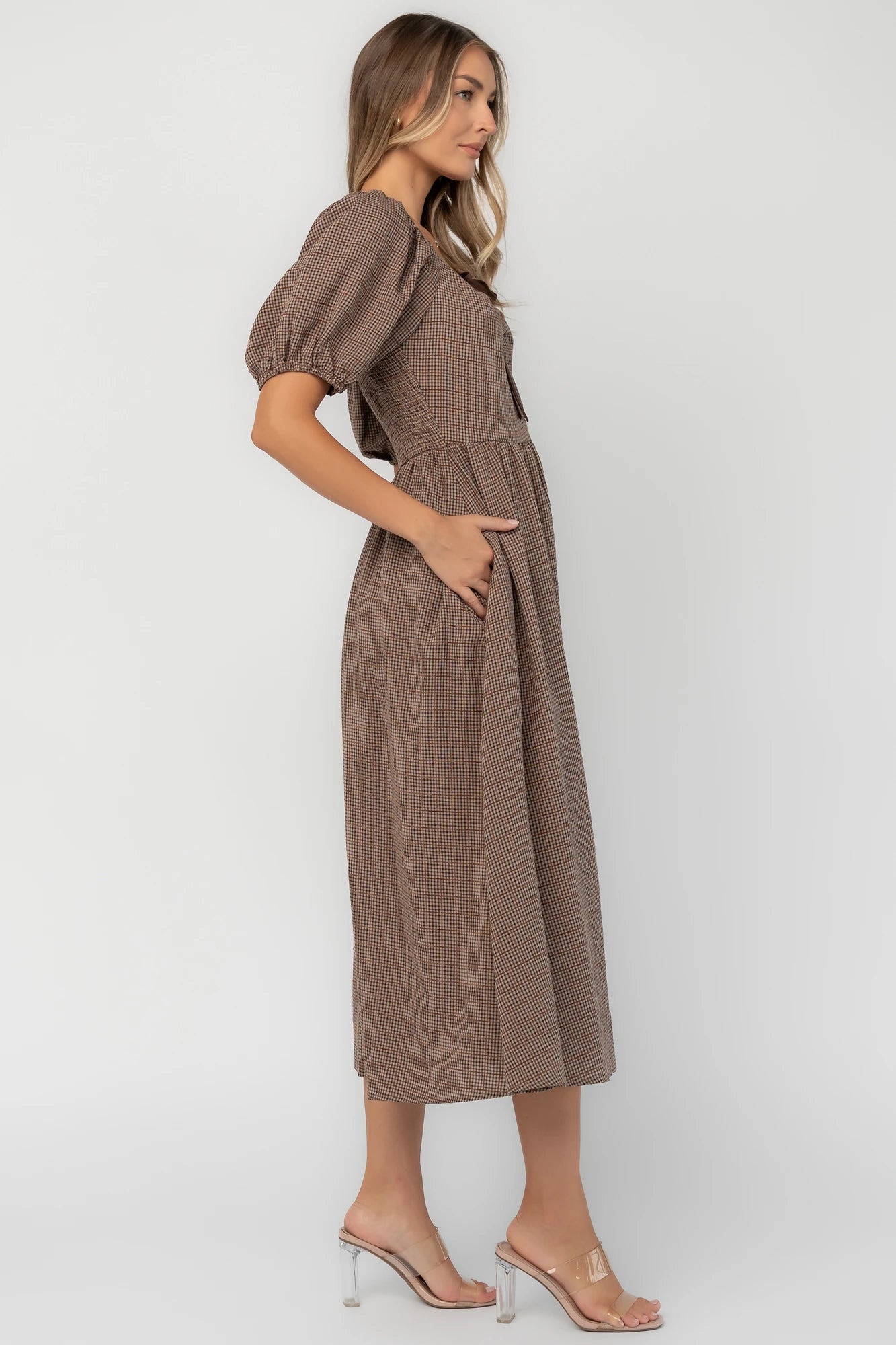 Mocha gingham midi dress with a square neckline, puff sleeves, smocked back, side pockets, and a flowing tiered skirt.