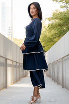 Styled outfit image of navy Barcelona dress paired with neutral sandals, showing midi length, sweetheart neckline, and ivory trim details.