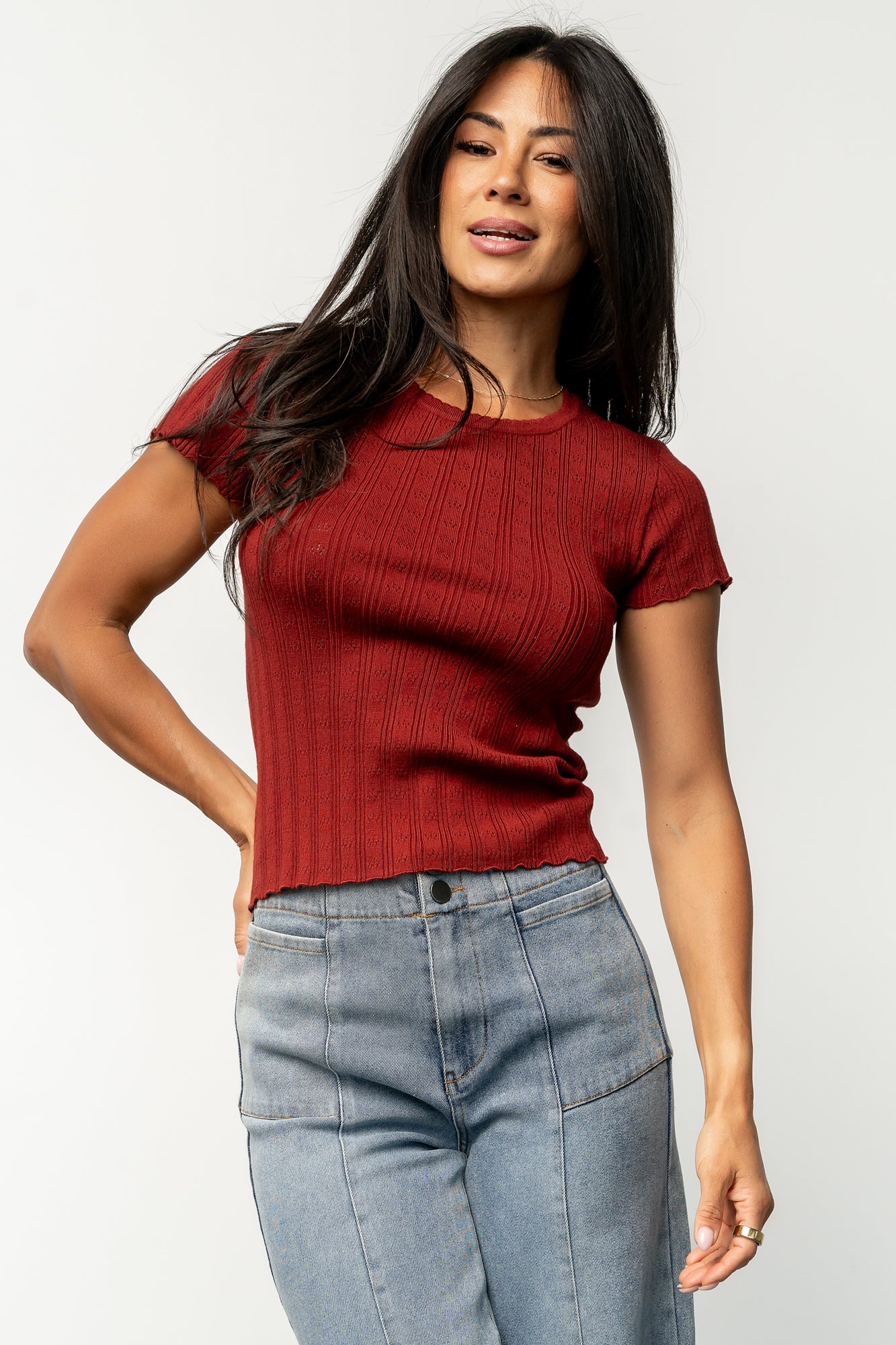Styled flat-lay of the Penny Pointelle top in brick, highlighting scalloped edges, lightweight knit, and warm brick color.