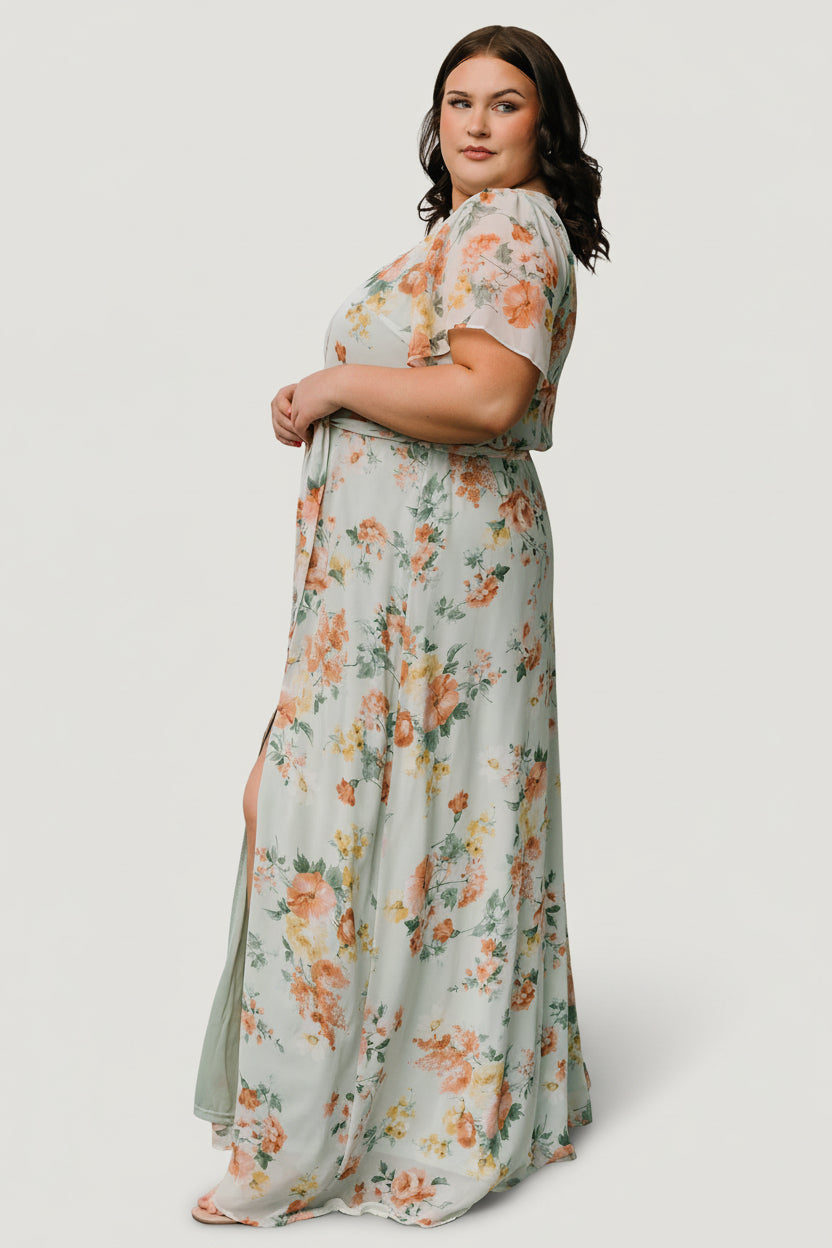 Styled outfit photo showing the sage floral maxi worn with low heels, emphasizing length, drape, and occasion-ready styling details.