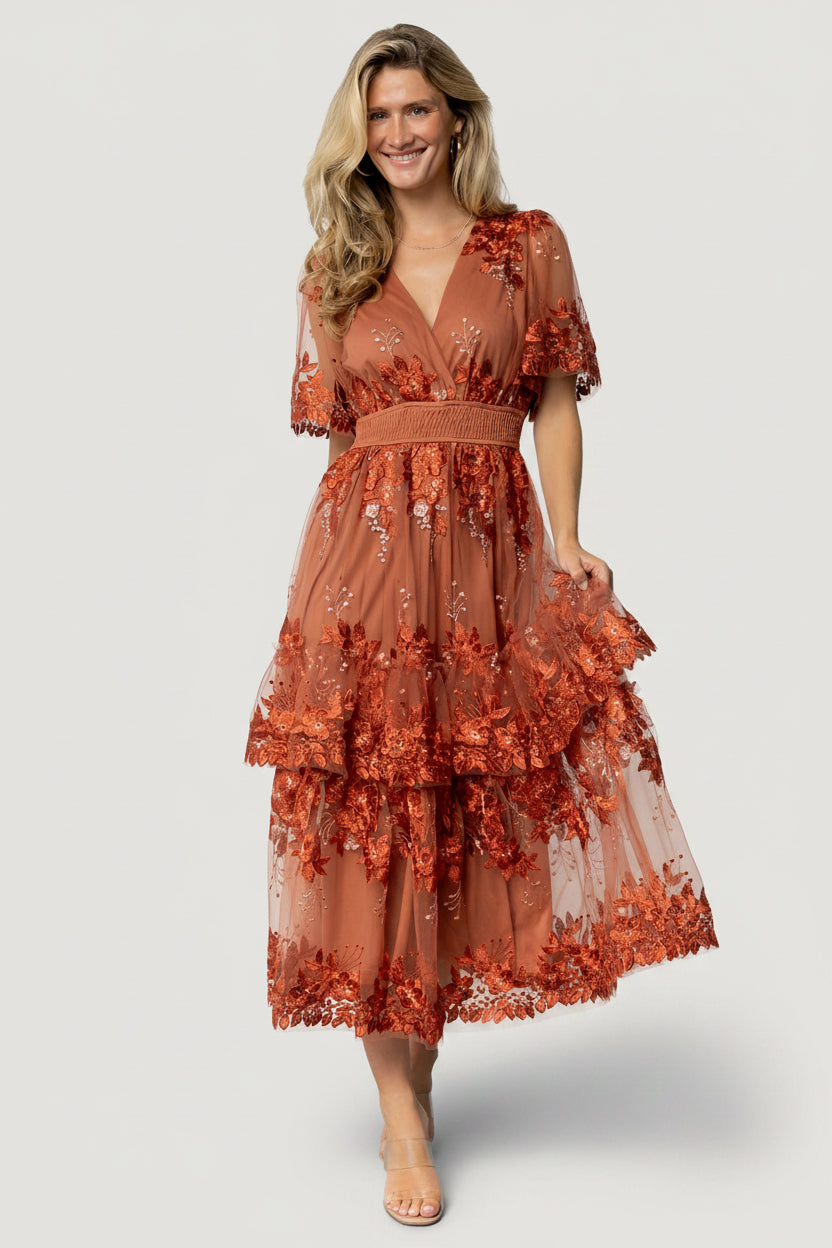 Back view of the Lotte embroidered midi dress in rust showing skirt length, subtle gather at smocked waistband, and embroidered pattern.