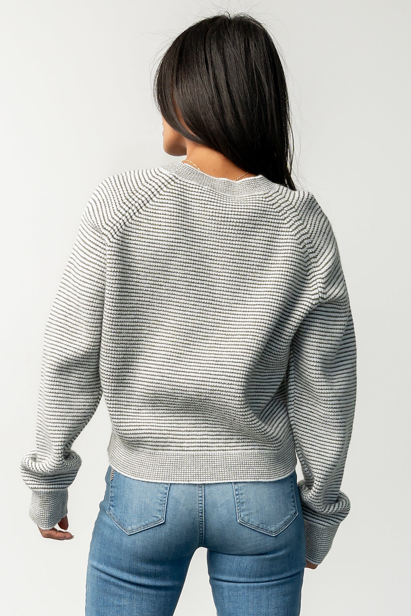 Styled outfit image presenting the Zadie Striped Sweater tucked at front into jeans, illustrating versatile styling options for daywear.