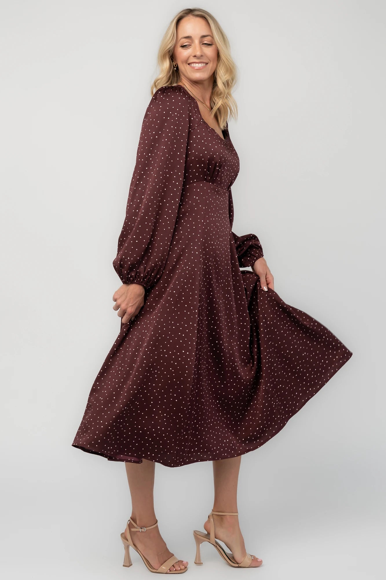 Mahogany brown midi dress with a square neckline, long sleeves, smocked back waist, removable back bow, side pockets, and a flowing skirt with heart details.