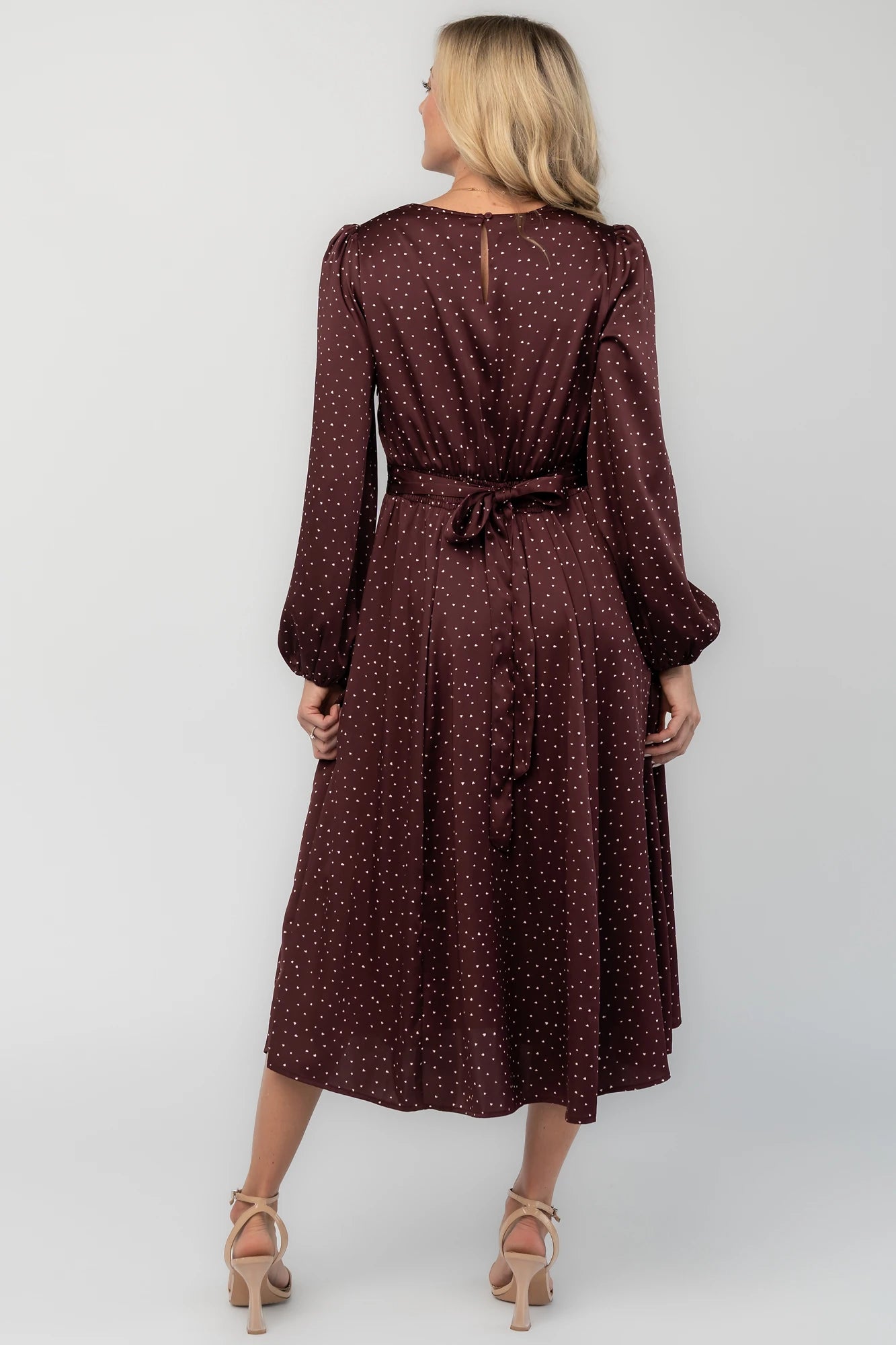 Mahogany brown midi dress with a square neckline, long sleeves, smocked back waist, removable back bow, side pockets, and a flowing skirt with heart details.