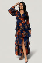 Front view of Mariella Tiered Maxi Dress in navy and rust floral chiffon, showing V-neckline, smocked back, and tiered ruffle skirt for occasion wear.