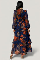 Side view of Mariella Tiered Maxi Dress showing cascading ruffles, maxi length and flowing chiffon movement in navy and rust floral print.