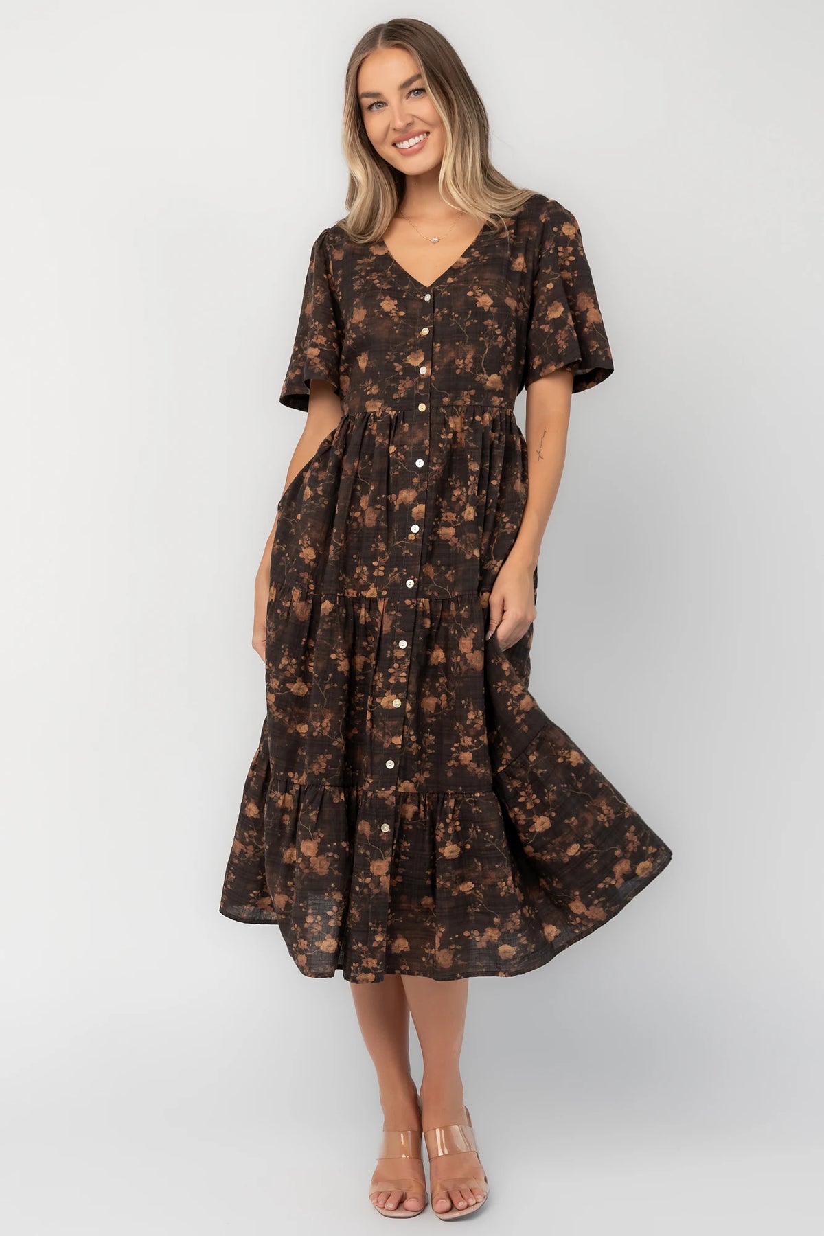 Clove floral midi dress with a V-neckline, functional button-front closure, puff sleeves, elastic back waist, side pockets, and a tiered skirt.