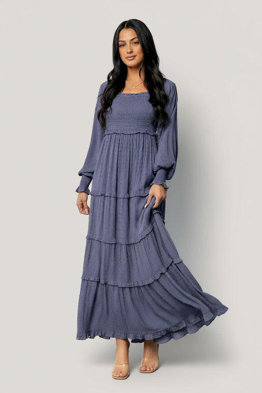 Front view of model wearing Amanda smocked dotted maxi dress in dusk blue, highlighting square neckline, smocked bodice, and long sleeves.