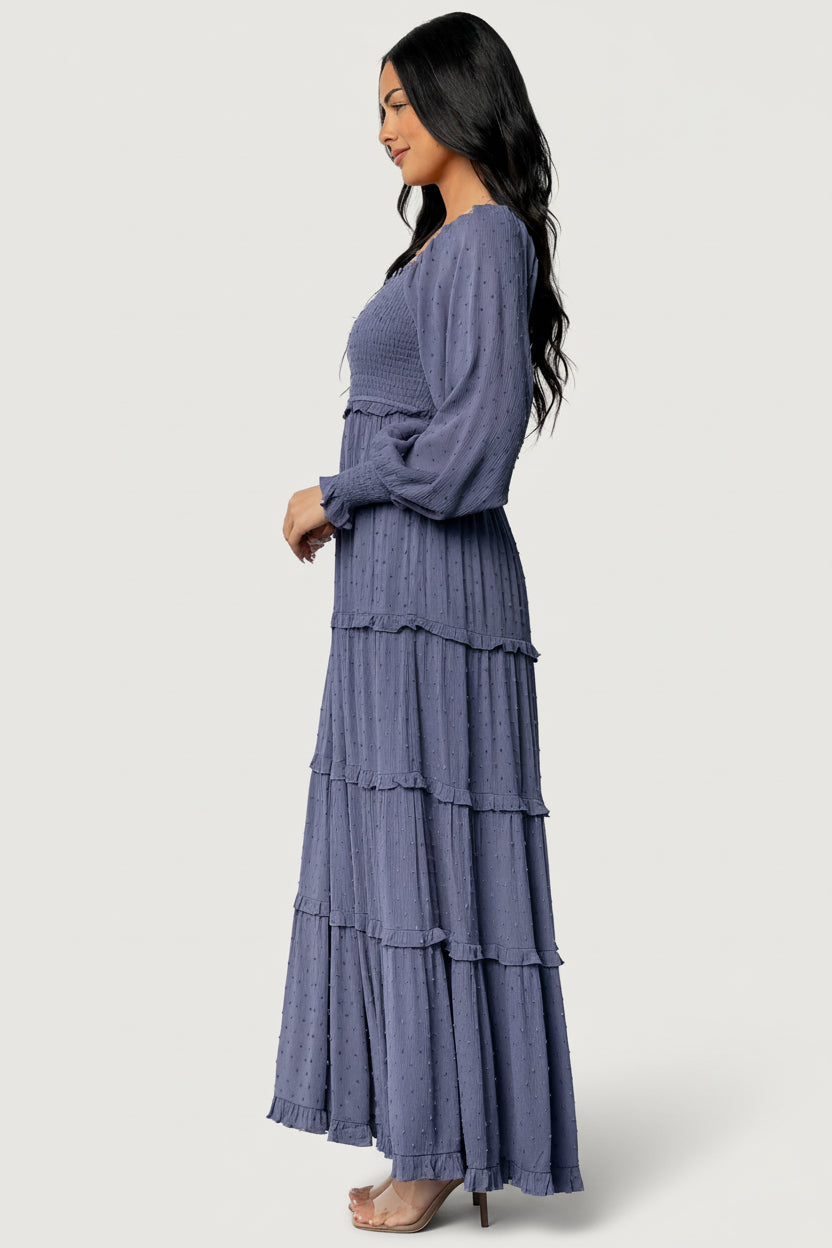 Styled look of the Amanda dusky blue smocked maxi dress paired with simple accessories, showcasing versatility from day to evening.
